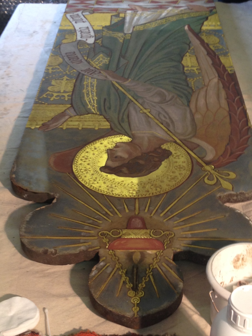 Gabriel reredos panel laid flat on the workbench with cotton swabs and cleaning materials
