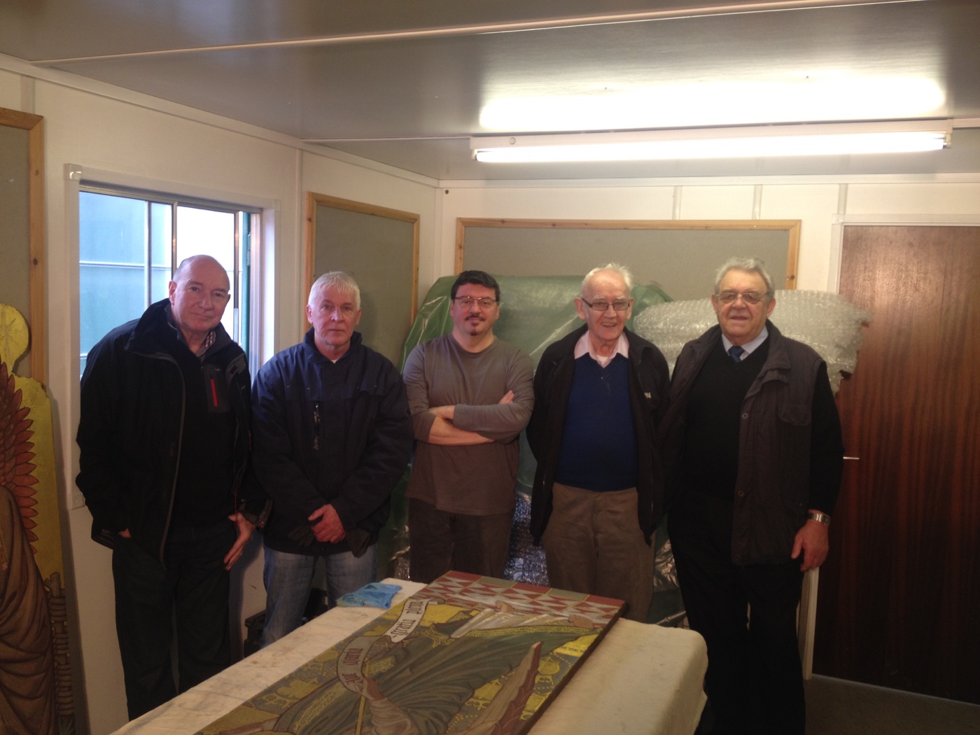 Silvano Cioci-Faux standing with workshop visitors behind the altar panel on the table