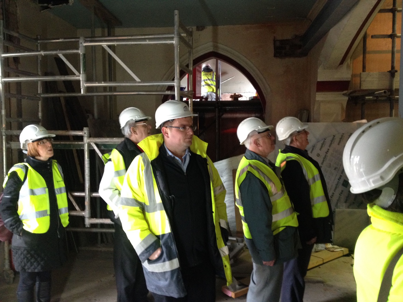 Heritage workshop attendees in hi-vis vests touring the church interior during building works