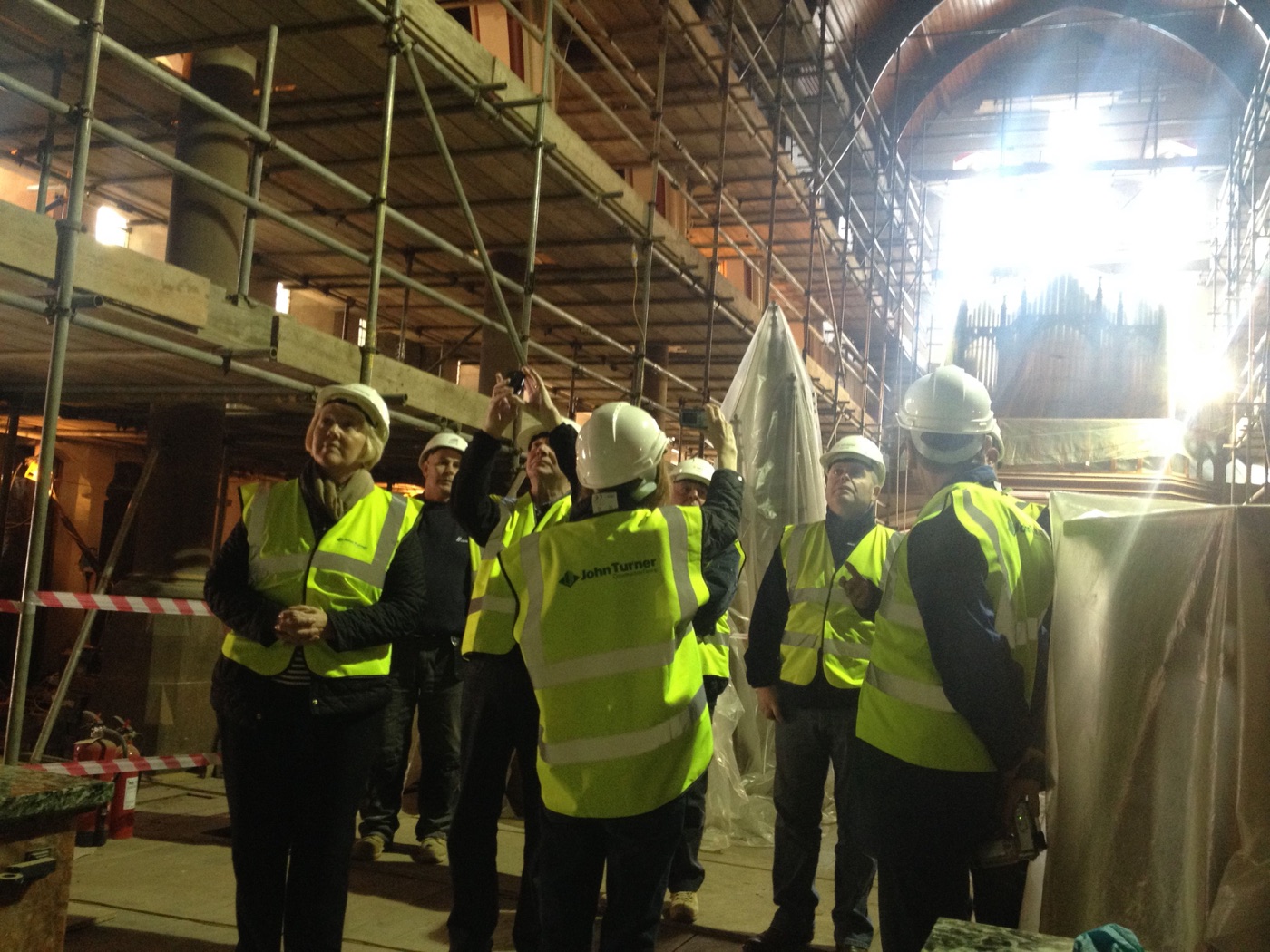 Heritage workshop group in hard hats viewing St Marie's nave and organ through scaffolding