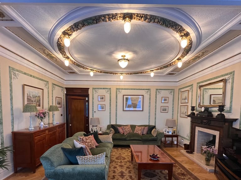 Victorian drawing room with hand-cut stencil panels, botanical corner motifs and a coffered ceiling