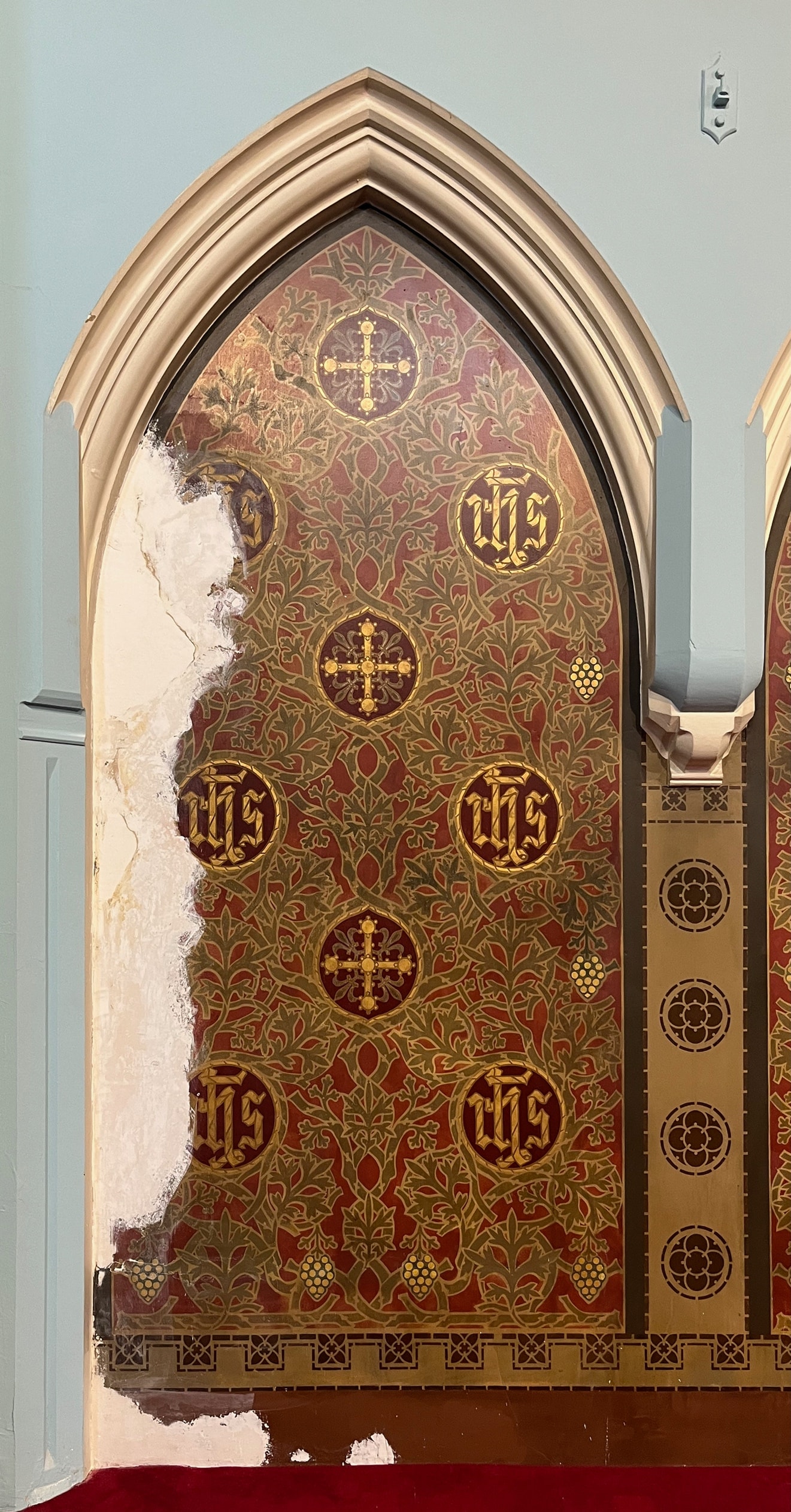 Gothic arch stencil scheme at St Francis de Sales Church before restoration, showing plaster loss